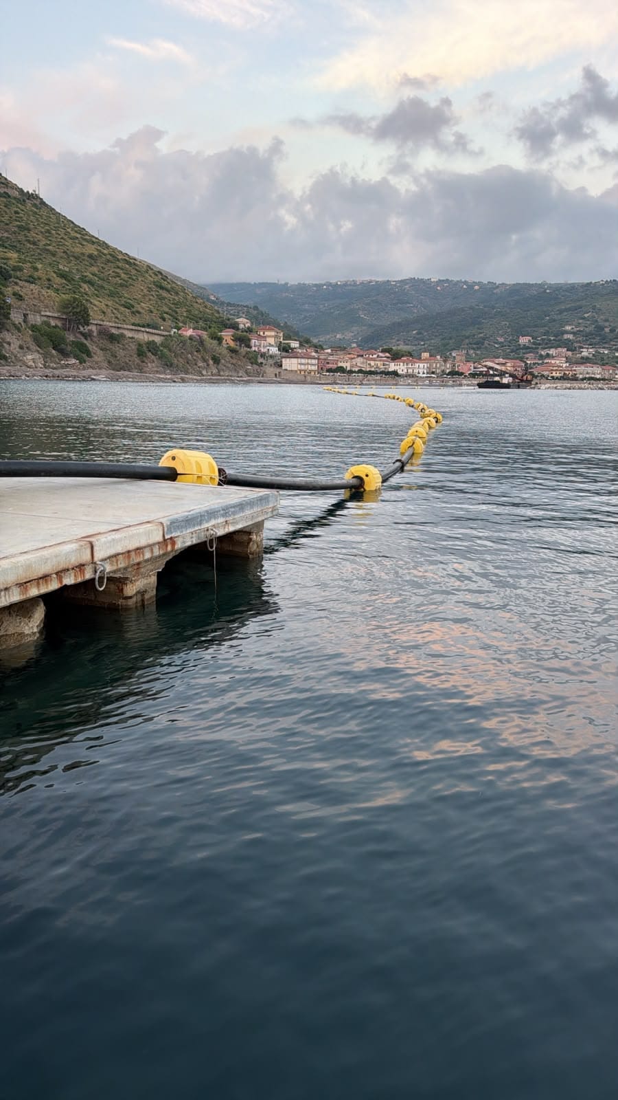 Dredging pipeline with yellow floats next to a pier in Montecorice